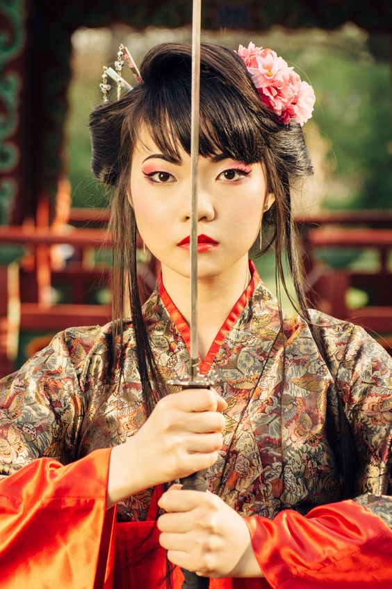 Beautiful korean woman or geisha in kimono holding samurai sword near face